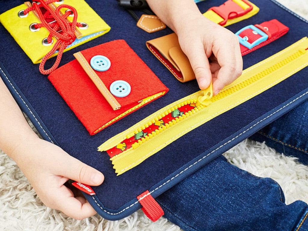 Gyerekkéz gombolja a Teaisiy Montessori fejlesztő tábla piros filczsebét