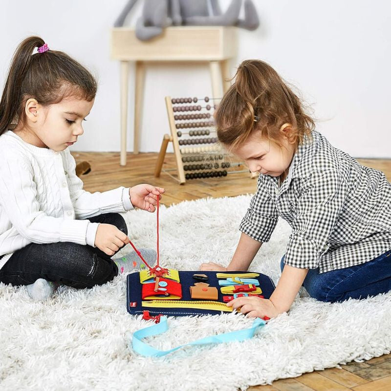 Két kisgyerek játszik a Teaisiy Montessori busy boarddal a szőnyegen