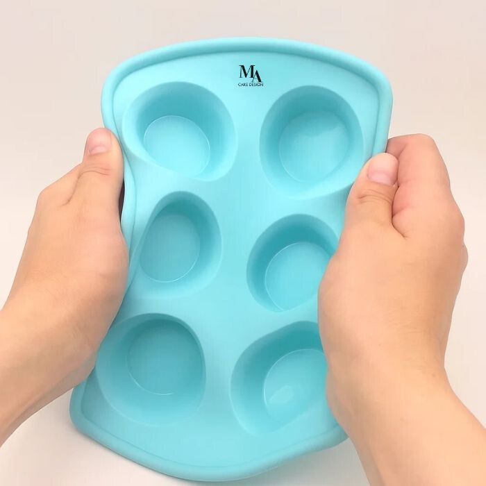 Hajlítható szilikon muffinforma két kézben tartva, rugalmas anyag