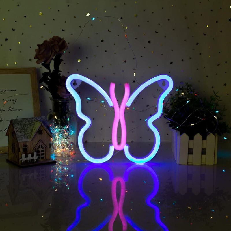 Kék-rózsaszín pillangó LED lámpa asztalon, tükröződő felületen díszek között
