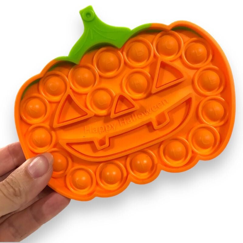 Milestar Pop It Halloween tök kézben tartva, a nyomkodós buborékok közelről